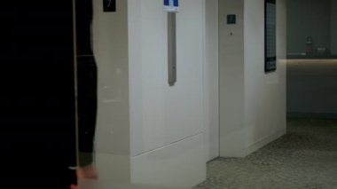 Adam yukarı çıkmak için asansör düğmesine basıyor. Yavaş moion