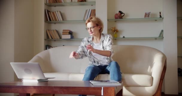 Woman look at laptop screen sit on sofa, Wide shot footage — Stockvideo