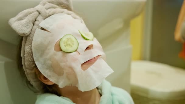 Two sisters play in spa treatments, put on cucumber rings and with a mask for skin care — Stock Video