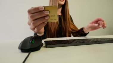 Bilgisayar klavyesine kredi kartı numarası yazan, online alışveriş yapan bir kadın.