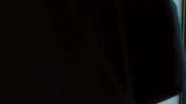 Siyah takım elbiseli bir iş adamı akıllı telefon kullanıyor ve pencereden gökdelenlere bakıyor..