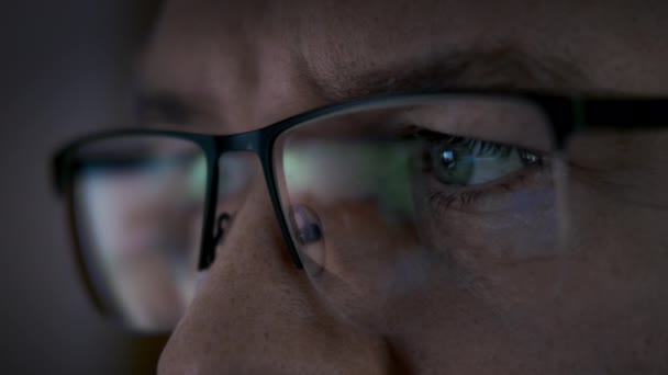 Reflexão de uma tela no homem Óculos à noite, Homem de negócios usando, navegando na internet, assistindo dinâmica de negócios em estoque — Vídeo de Stock