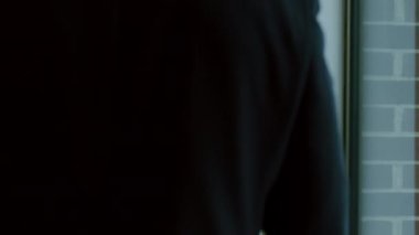 Siyah takım elbiseli bir iş adamı binalara bakan büyük bir pencereye doğru yürüyor. Yavaş çekim görüntüleri