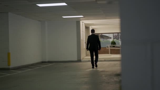 Un uomo d'affari vestito di nero cammina nel parcheggio. Rallentatore — Video Stock