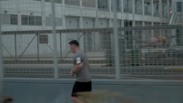 Молодий спортсмен зі спортивним тілом біжить з зусиллями і відданістю в центрі міста. Вид збоку — стокове відео