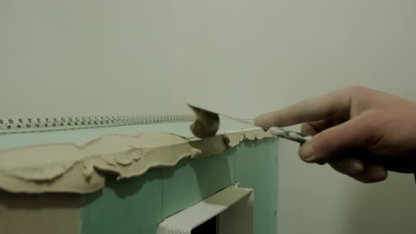 Close-up zicht op de hand van de meester klei de muur met een spatel. Woningrenovatie — Stockvideo