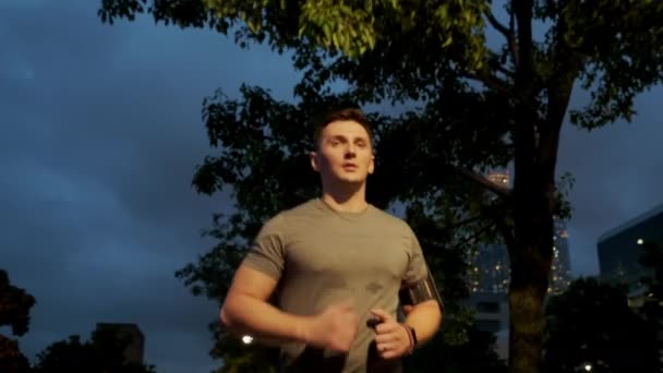 Young male sportsman with athletic body is running with effort and dedication in city center. Front view Close up — Vídeo de Stock