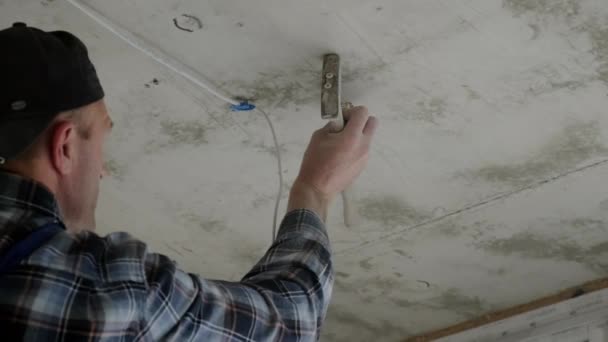 The worker installs the mounting for the LED lamp which will be placed on the suspended ceiling — Wideo stockowe