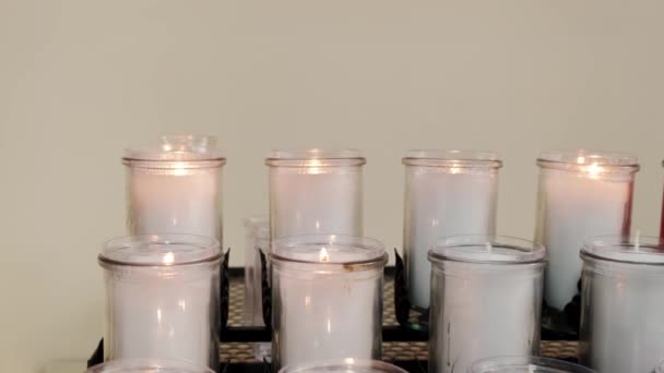 Κοντινό πλάνο με κόκκινα και λευκά κεριά να καίγονται στην ορθόδοξη εκκλησία. Μετακίνηση βίντεο κάμερας — Αρχείο Βίντεο