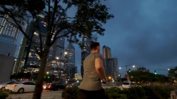 Young male sportsman with athletic body is running with effort and dedication in city center. Side Close up view — Wideo stockowe