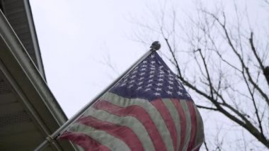 Close up shot of American Flag on a front porch on a breezy day.
