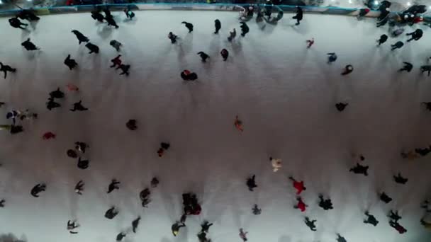 Aerial drone view of people skating on an outdoor skating rink in winter at night in City, with dark nighttime lighting. — стокове відео