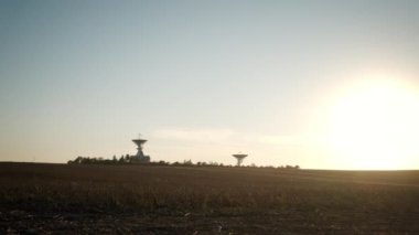 Wide view footage of two telecommunications antenna or Radio telescope satellite dish on sunset