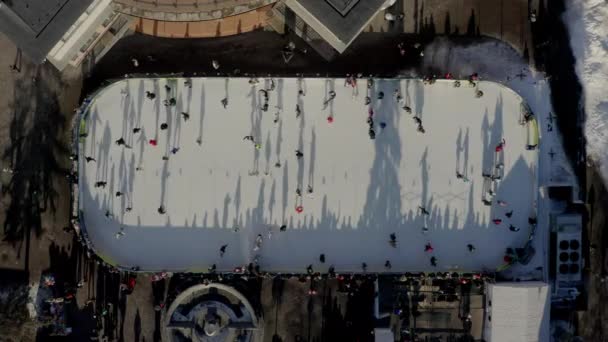 Drüber Drohnenbild von Menschen, die im Winter in City auf einer Eisbahn im Freien Schlittschuh laufen — Stockvideo