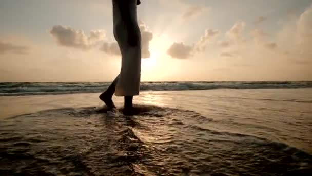 Gün batımında güzel bir sahilde yürüyen genç bir kadının silueti.. — Stok video