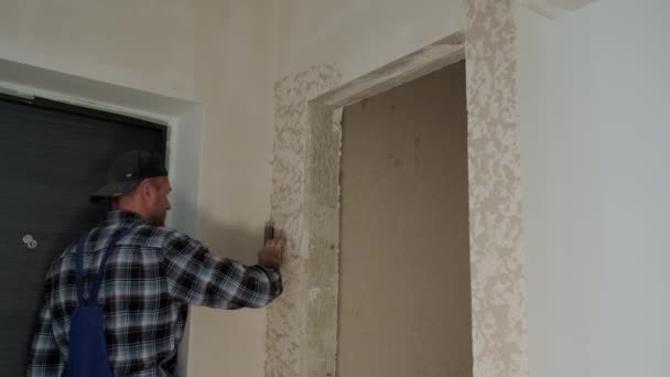 Wide view of Worker puts decorative plaster on the wall, forming a relief — Stock Video