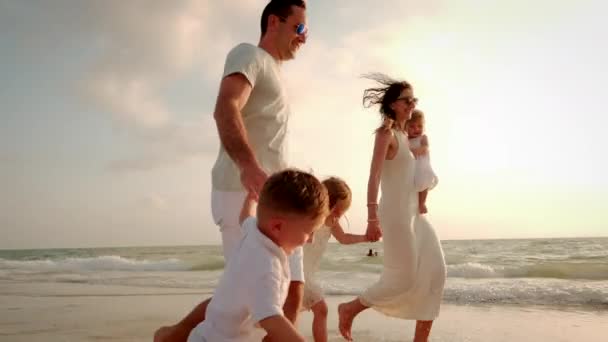 Güzel bir gün batımında sahilde koşan mutlu ve neşeli bir aile. — Stok video