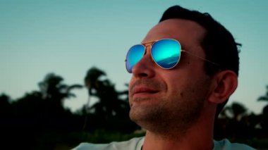 Gün batımında gözlüklü bir adamın portresi.