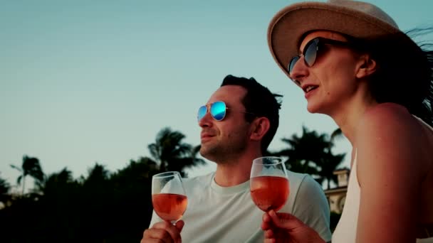 夫婦は海の夕日に対してワインと彼らの手の中に2つのメガネを取ります.スローモーション映像 — ストック動画
