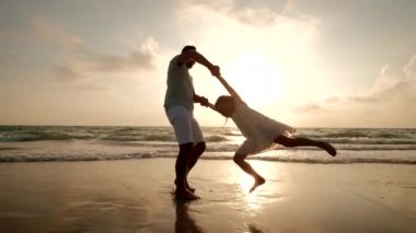 Mutlu baba ve kızı gün batımında sahilde oynarken