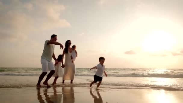 아름다운 일몰에 해변을 뛰어다니는 행복 한 가족. 넓은 샷 — 비디오