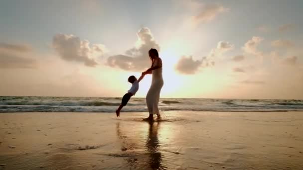 Mutlu anne ve oğul gün batımında sahilde oynuyorlar. — Stok video