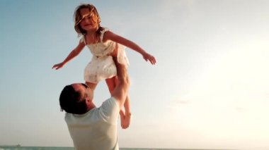 Mutlu baba-kız gün batımında sahilde oynuyorlar. Kapat.