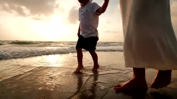 Madre e hijo caminan juntos en la playa al atardecer, Primer plano — Vídeos de Stock