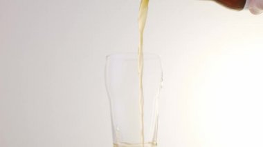 Beyaz arka planda bir şişeden bardağa bira doldurmak. Yavaş çekim Vercion 3