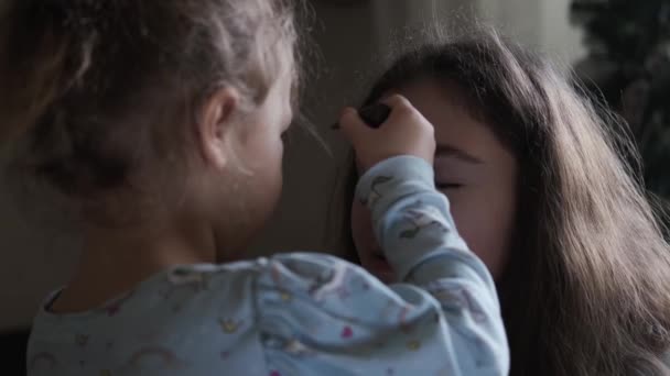 Kleines Mädchen spielt mit einem Schminkpinsel und stellt sich vor, wie sie ihren Freund schminkt. Nahaufnahme — Stockvideo