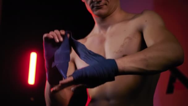 Mma lutador homem envolvendo suas mãos em fita de boxe antes de uma luta de perto — Vídeo de Stock
