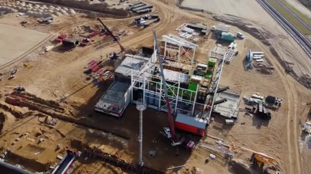 Vol aérien au-dessus d'un site de développement de nouvelles constructions Projets d'entrepôts et machinerie lourde et travailleurs de la construction travaillent dans la région. — Video