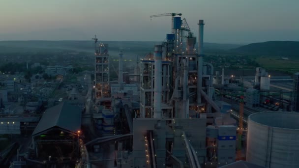 Цементный завод с высокой производственной структурой на территории промышленного производства на закате. Видеозапись беспилотника 4k — стоковое видео