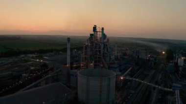 Gün batımında endüstriyel üretim alanında yüksek fabrika yapısına sahip çimento fabrikası. Hava aracı görüntüleri 4k