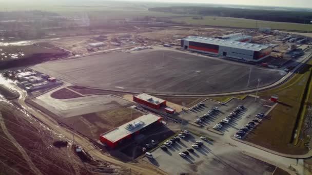 Luftflug über einer Neubausiedlung: In dem Gebiet arbeiten Lagerhäuser, schwere Maschinen und Bauarbeiter. Weite Sicht — Stockvideo