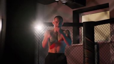 Dövüş sanatları dövüşçüsü spor salonunda kickboksla antrenman yapıyor. Manzarayı kapat. Yavaş çekim