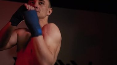 Dövüş sanatları dövüşçüsü spor salonunda kickboksla antrenman yapıyor. Yavaş çekim.