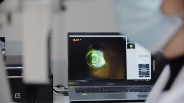 O oftalmologista examina o olho do paciente e, em seguida, olha para a câmera. Imagens de close up view — Vídeo de Stock