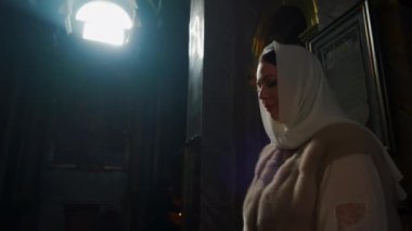 Bir kadın kilisede durup dua ediyor.