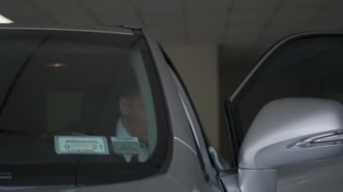 İş adamı otoparkta arabadan iniyor.