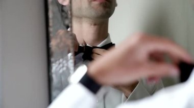 Damat beyaz gömleğini aynanın önünde düzeltir.