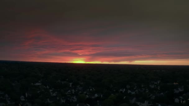 Вид з повітряного безпілотника на веселку під час заходу сонця, що летить над околицями будинків перед штормом — стокове відео