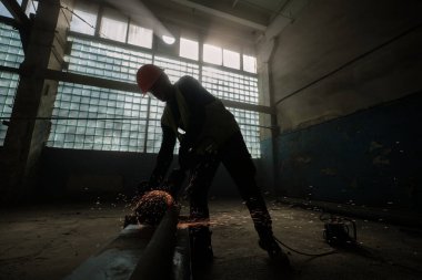 Profesyonel işçinin geniş açılı çekimi metali elektrikli testereyle kesiyor. 