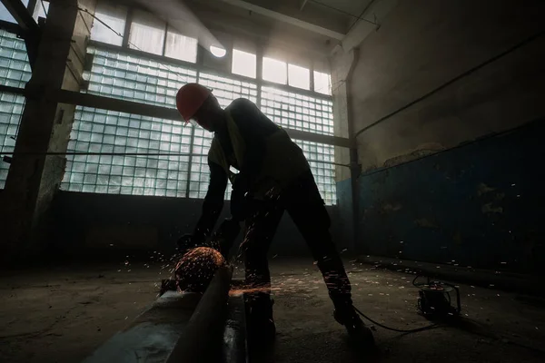 Profesyonel işçinin geniş açılı çekimi metali elektrikli testereyle kesiyor. 