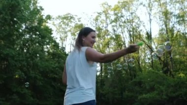 Sabun köpüğü üfleyen güzel bir kadının yavaş çekim görüntüleri. 