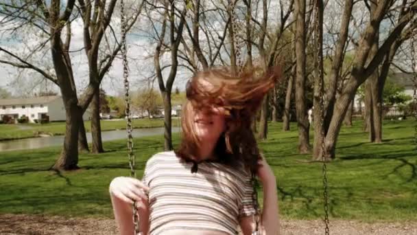 Mädchen auf einer Schaukel und glücklich lächelnd im Park. Zeitlupe — Stockvideo