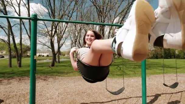 Girl on a swing and smiling happily in the park — Vídeo de Stock