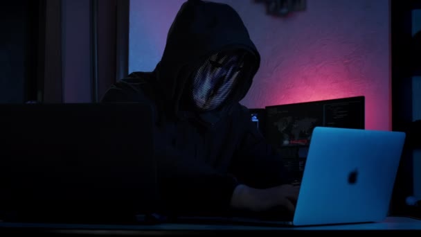 Unrecognizable hacker man in mask typing on keyboard and engaging hacking into security systems. Wide shot footage — Vídeos de Stock
