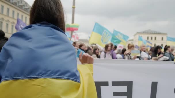 Fermer Manifestation populaire ukrainienne dans les rues de Munchen contre la guerre et contre le leader russe Poutine. personnes avec pancartes, drapeaux Europe, Deutschland Munchen, mai 2022 — Video