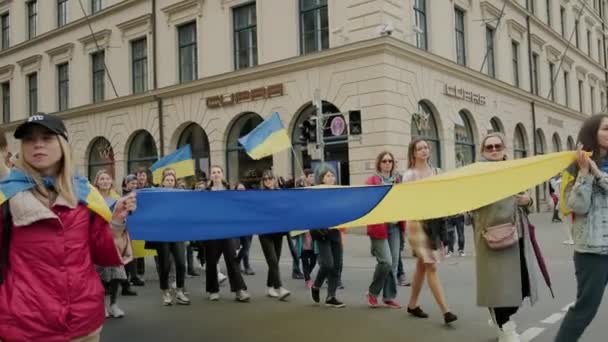 Oekraïners protesteren in de straten van München tegen de oorlog. Mensen met grote vlaggen Oekraïne, Duitsland München, mei 2022 — Stockvideo